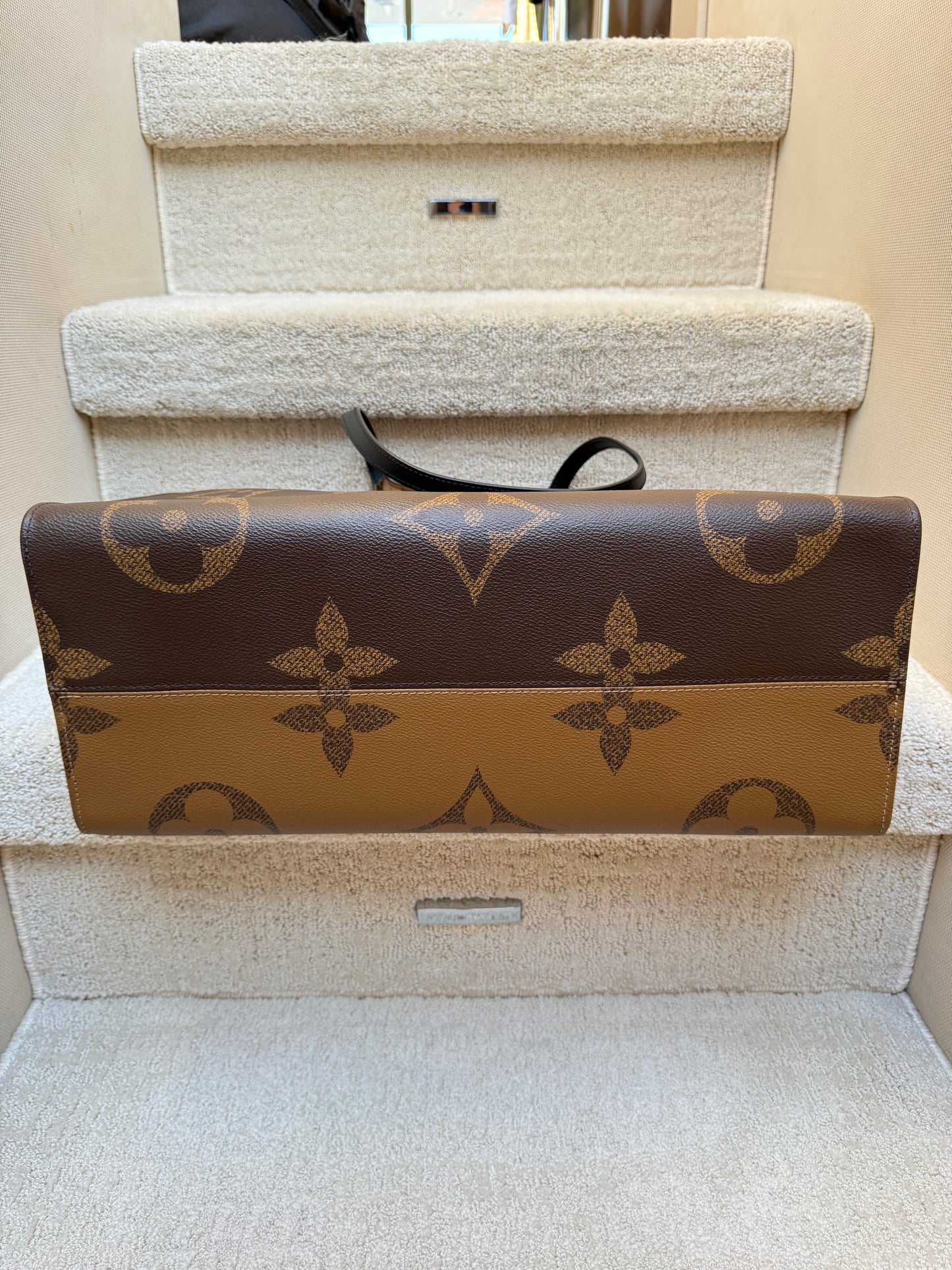 Photo of bottom of louis vuitton on the go tote in monogram brown showing no wear