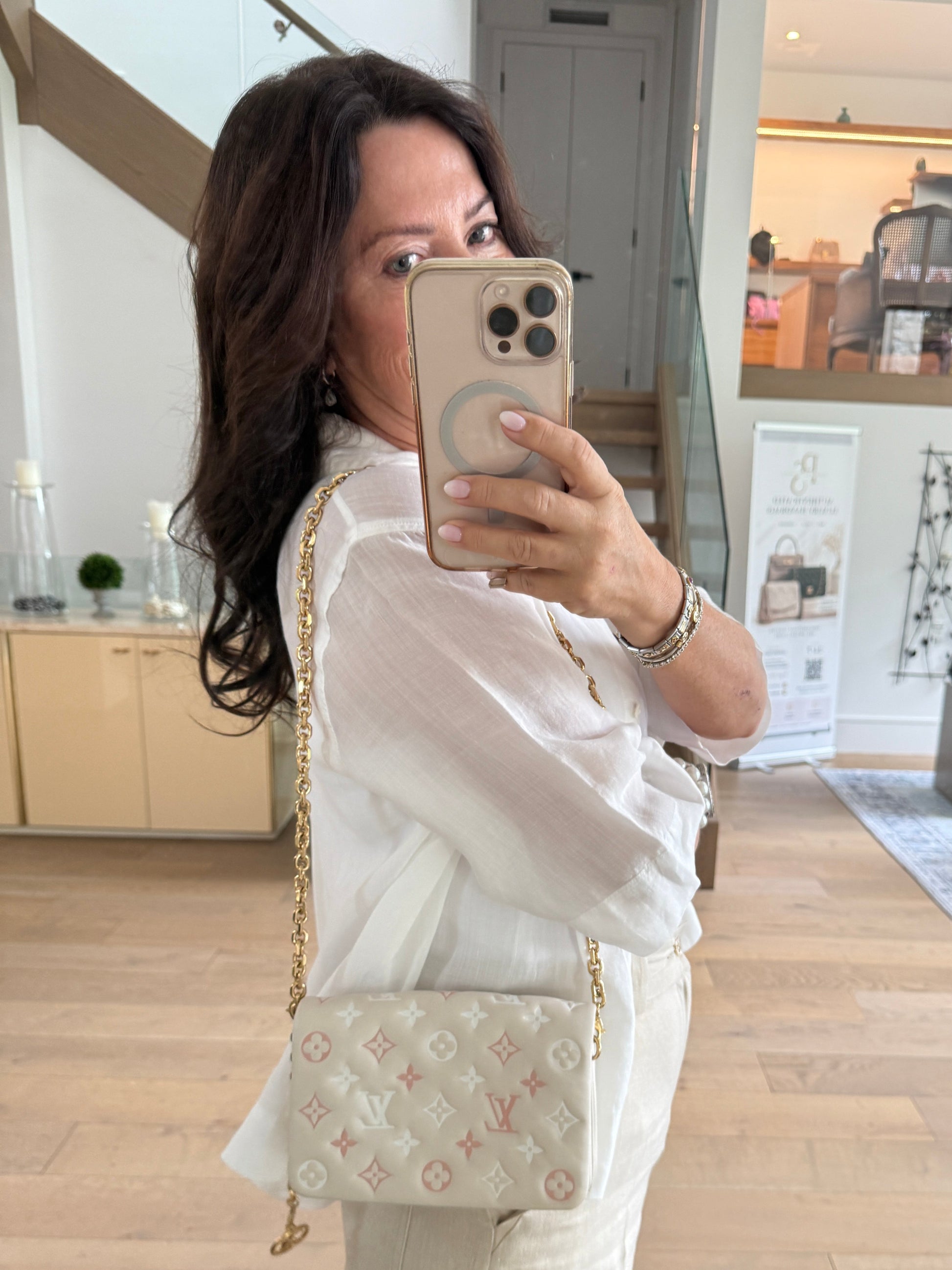 Louis Vuitton coussin pochette in cream with pink and white accent shown on woman worn as a shoulder bag with a hanging gold charm
