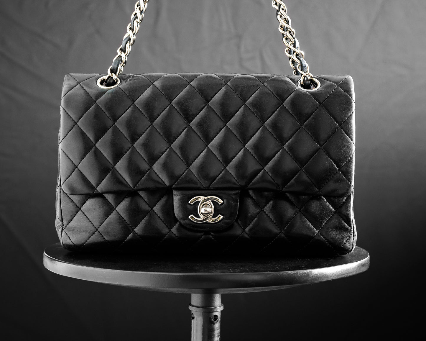 Chanel classic double flap in medium size with silver hardware and black lambskin is offered for sale under consignment.