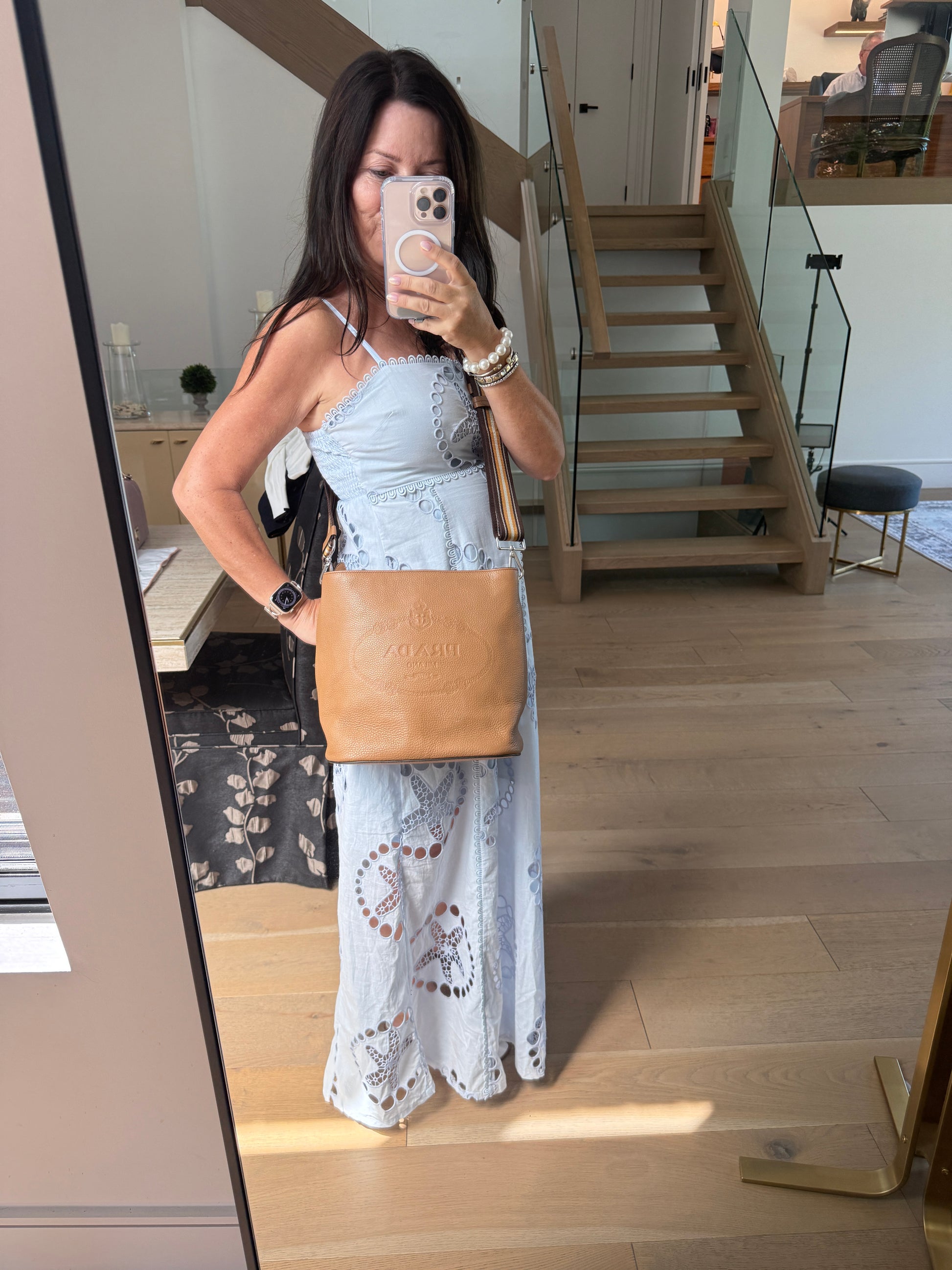 Another photo from the front of a woman wearing a prada camel bucket bag as a crossbody resale excellent condition