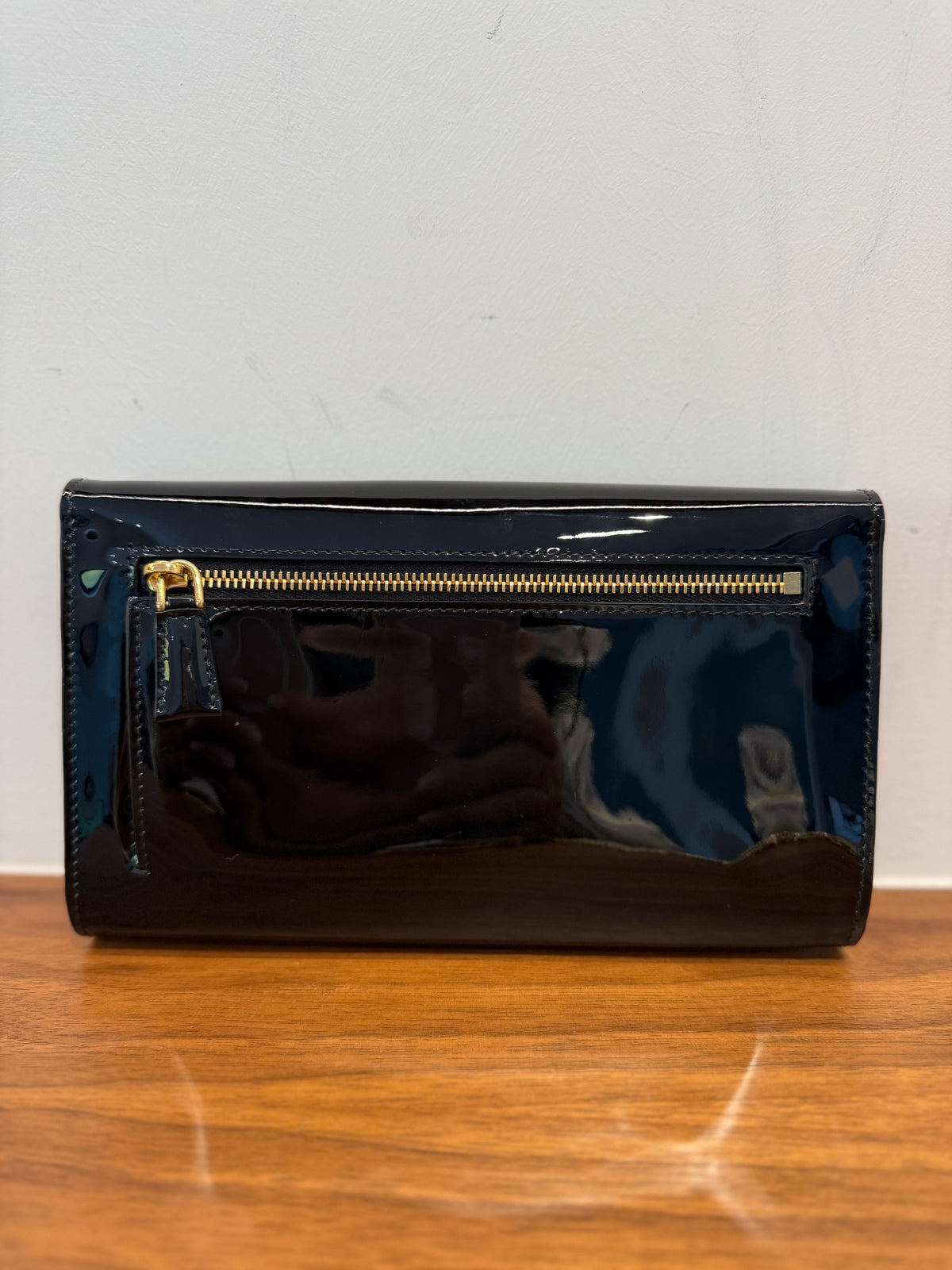 A glossy black patent Prada leather clutch wallet with a gold zipper view of back of clutch used for sale