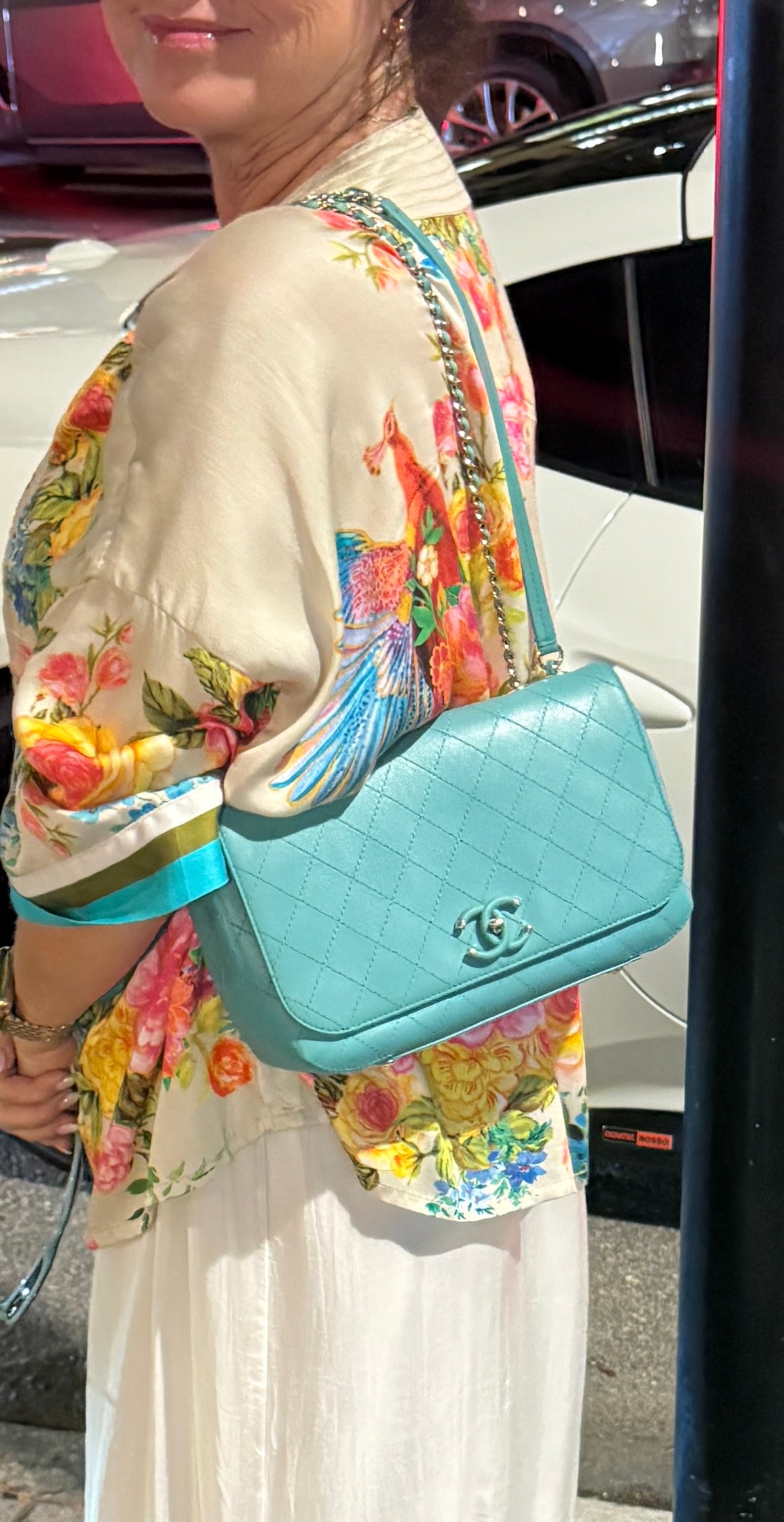 Woman wearing chanel medim classic flap handbag for sale in turquoise doubled up on her shoulder