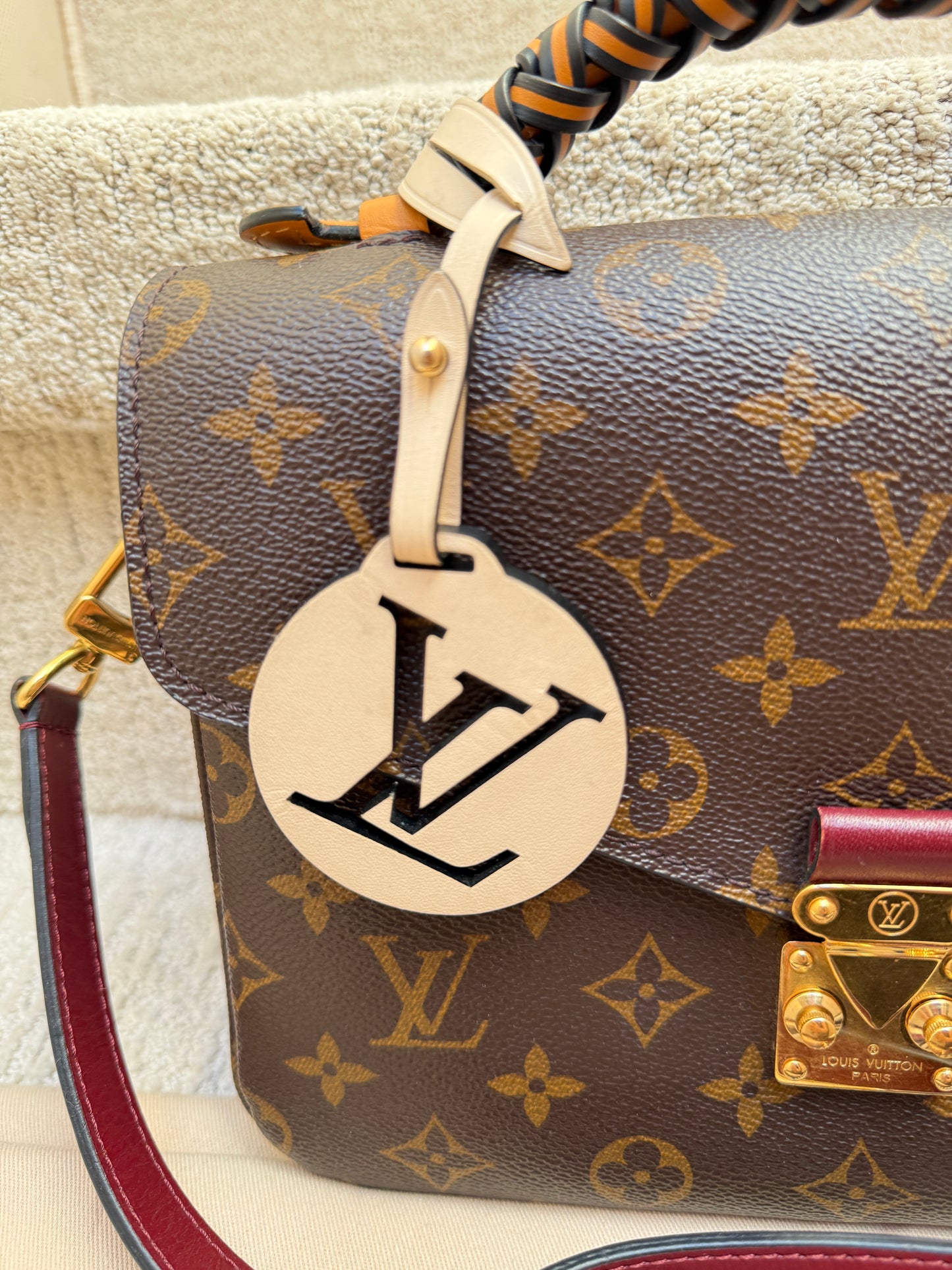 close up of the LV bag charm on an Louis Vuitton Pochette Metis for sale consignment