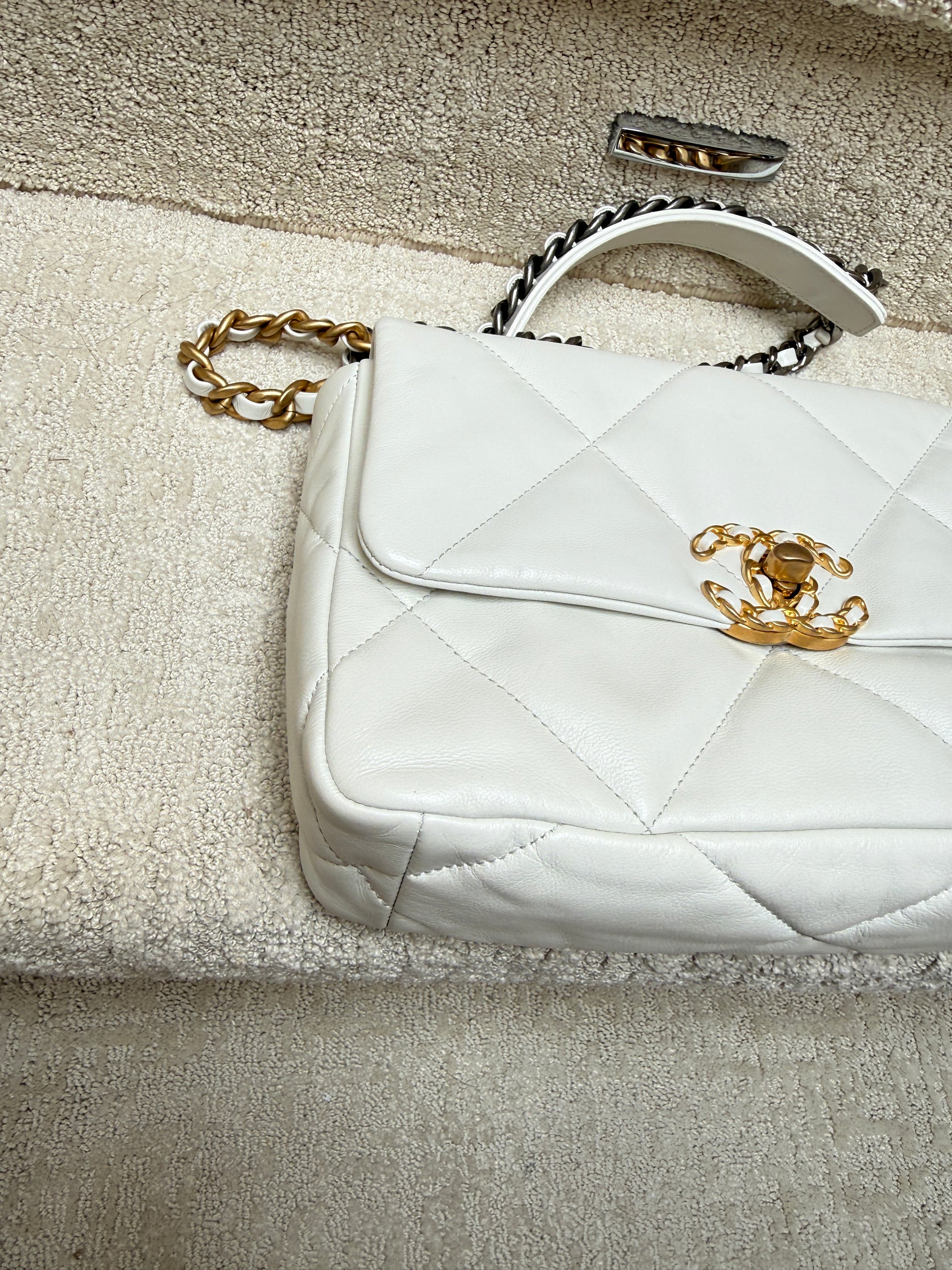 close up of front left corner of chanel 19 white leather handbag preloved