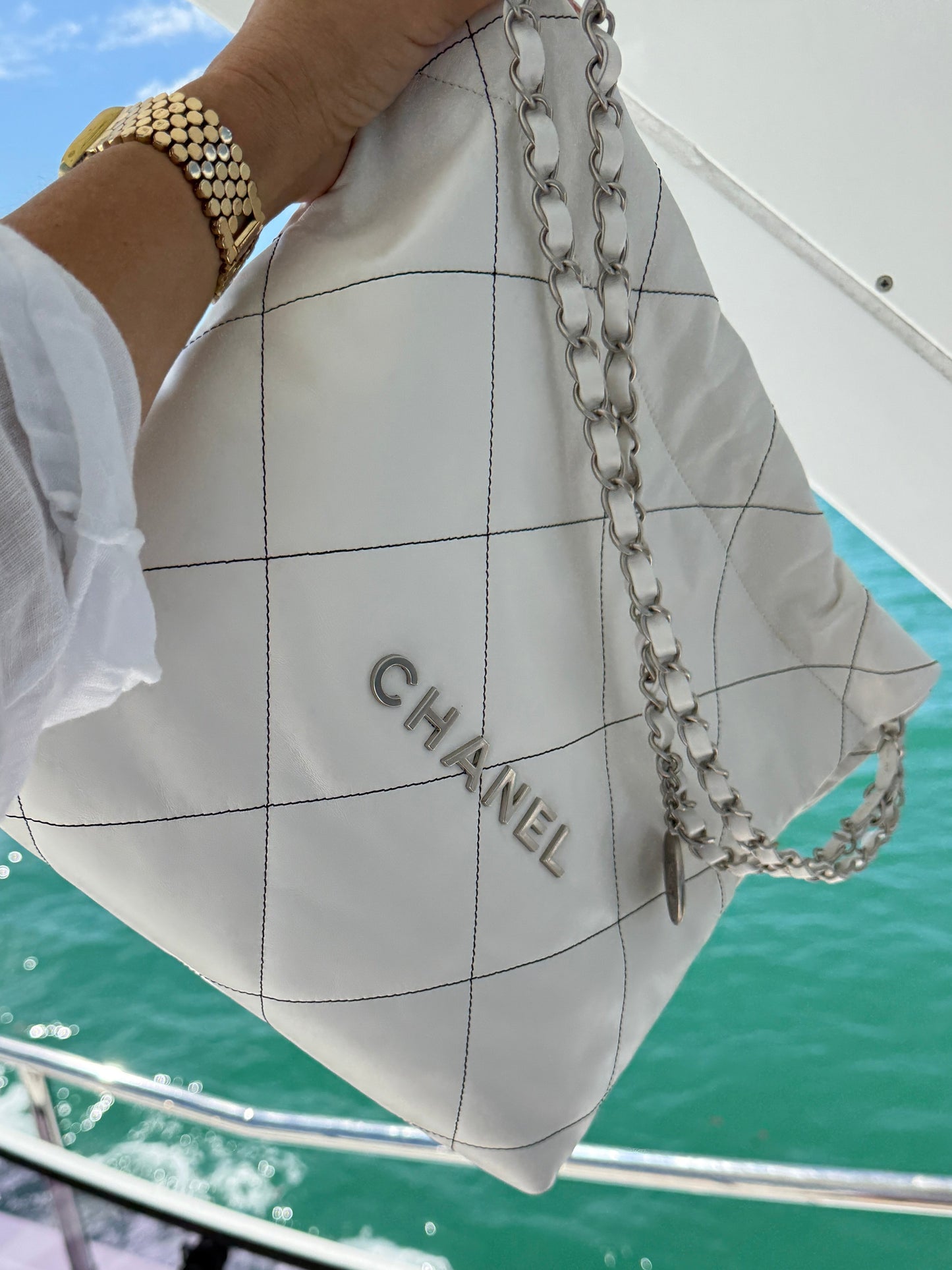 Chanel 22 in White with black stitching and silver hardware in likenew condition shown against ocean backdrop 