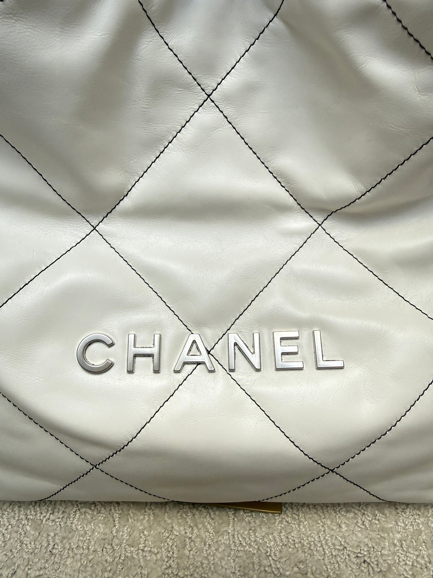 Close up of chanel front logo in silver on chanel 22 handbag in white