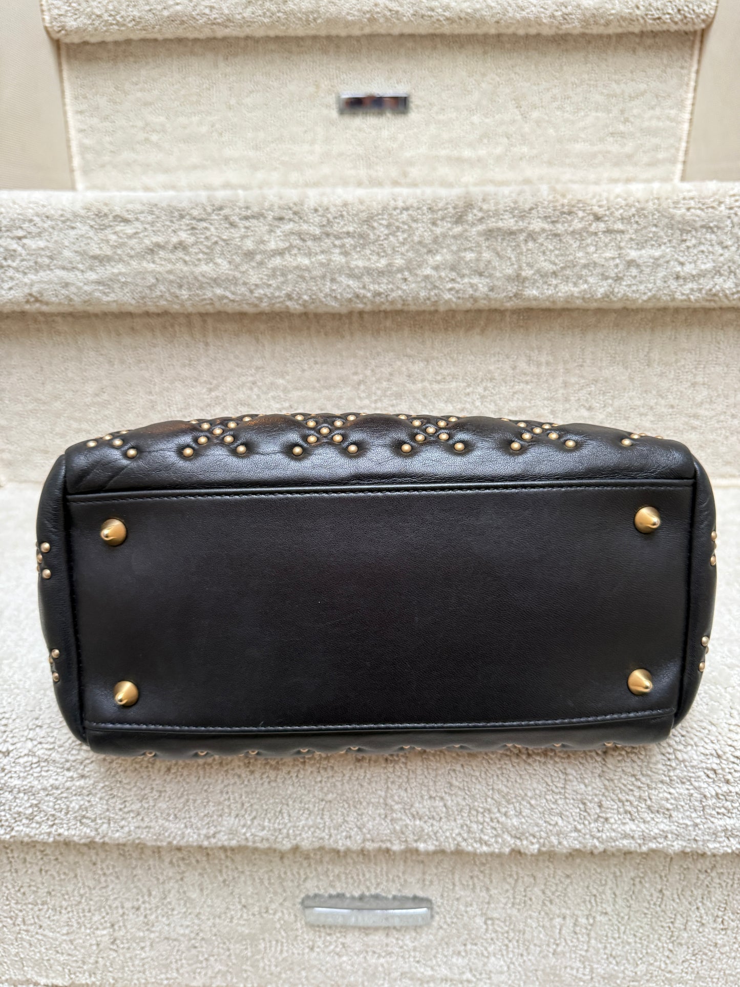 Lady Dior in size medium black leather with gold studs showing bottom of bag with feet