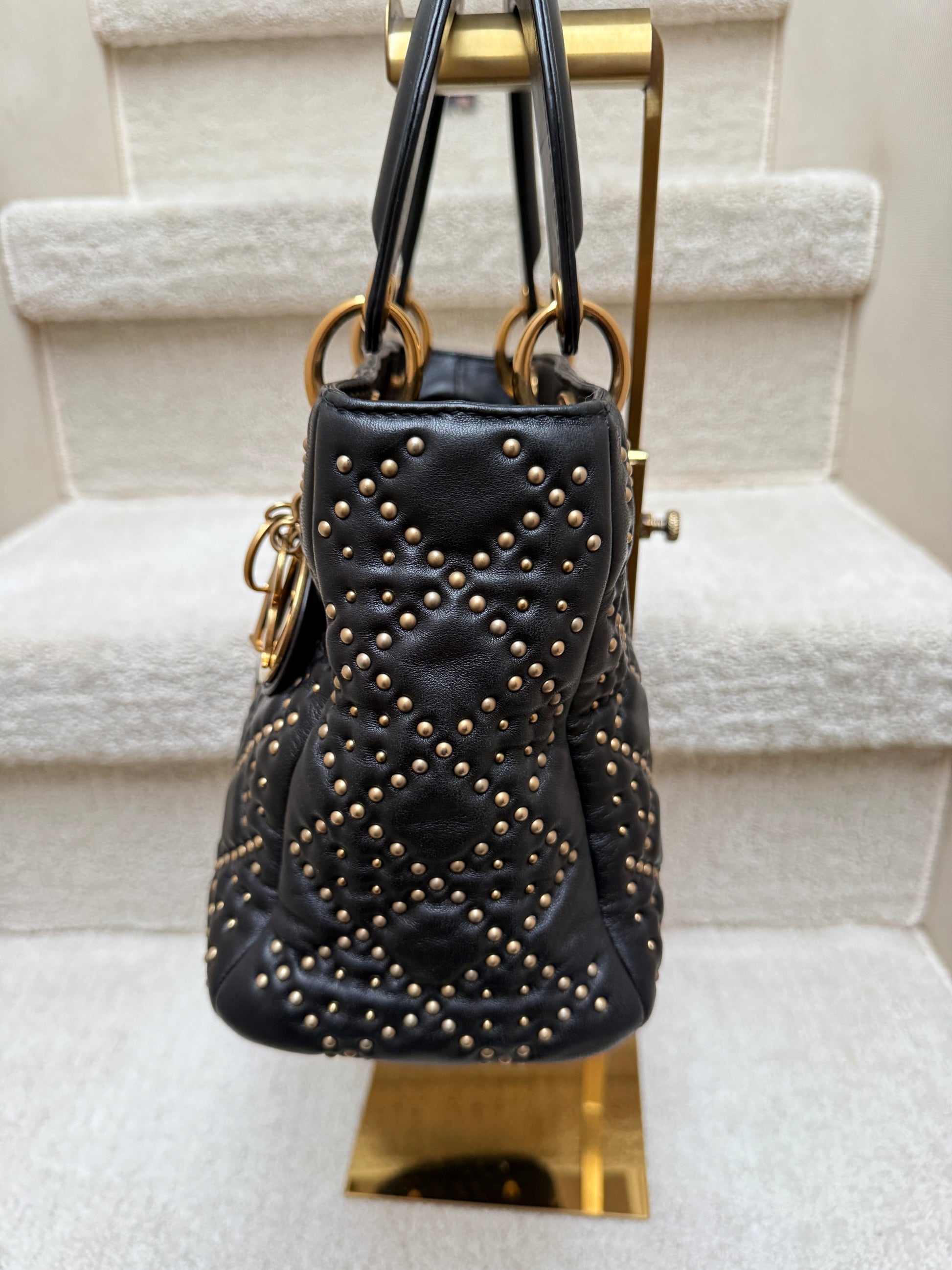 Side view of lady dior handbag preloved and authentic in soft black leather with gold stud accents