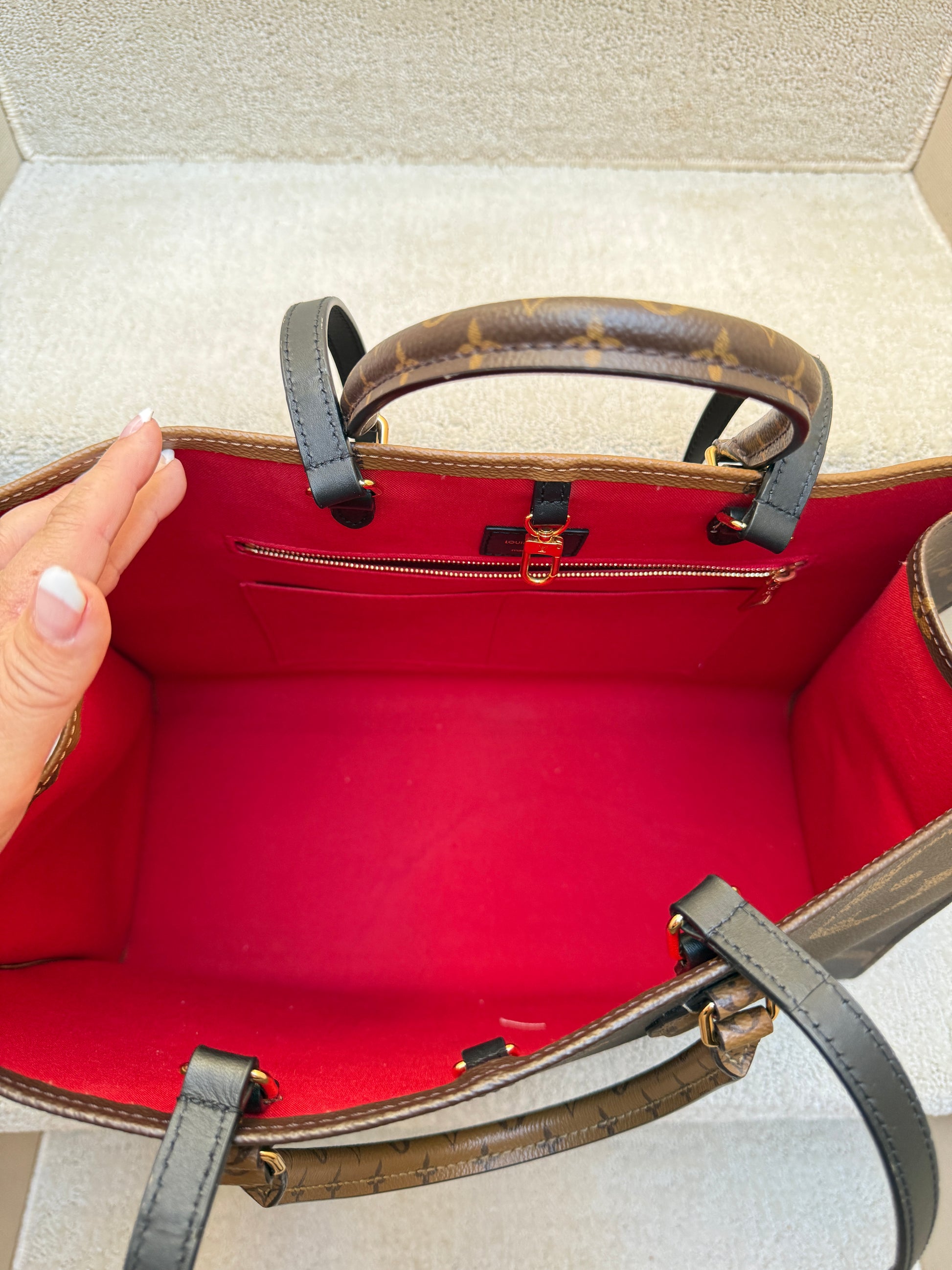 Red Interior of louis vuitton on the go handbag in gm size showing interior zipper and clasp and excellent condition