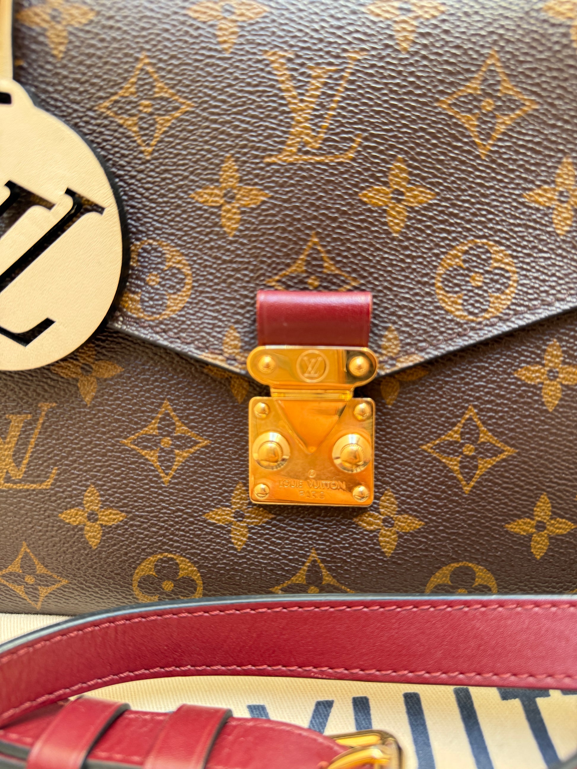 Close-up of a Louis Vuitton monogram handbag with gold hardware on pochette metis