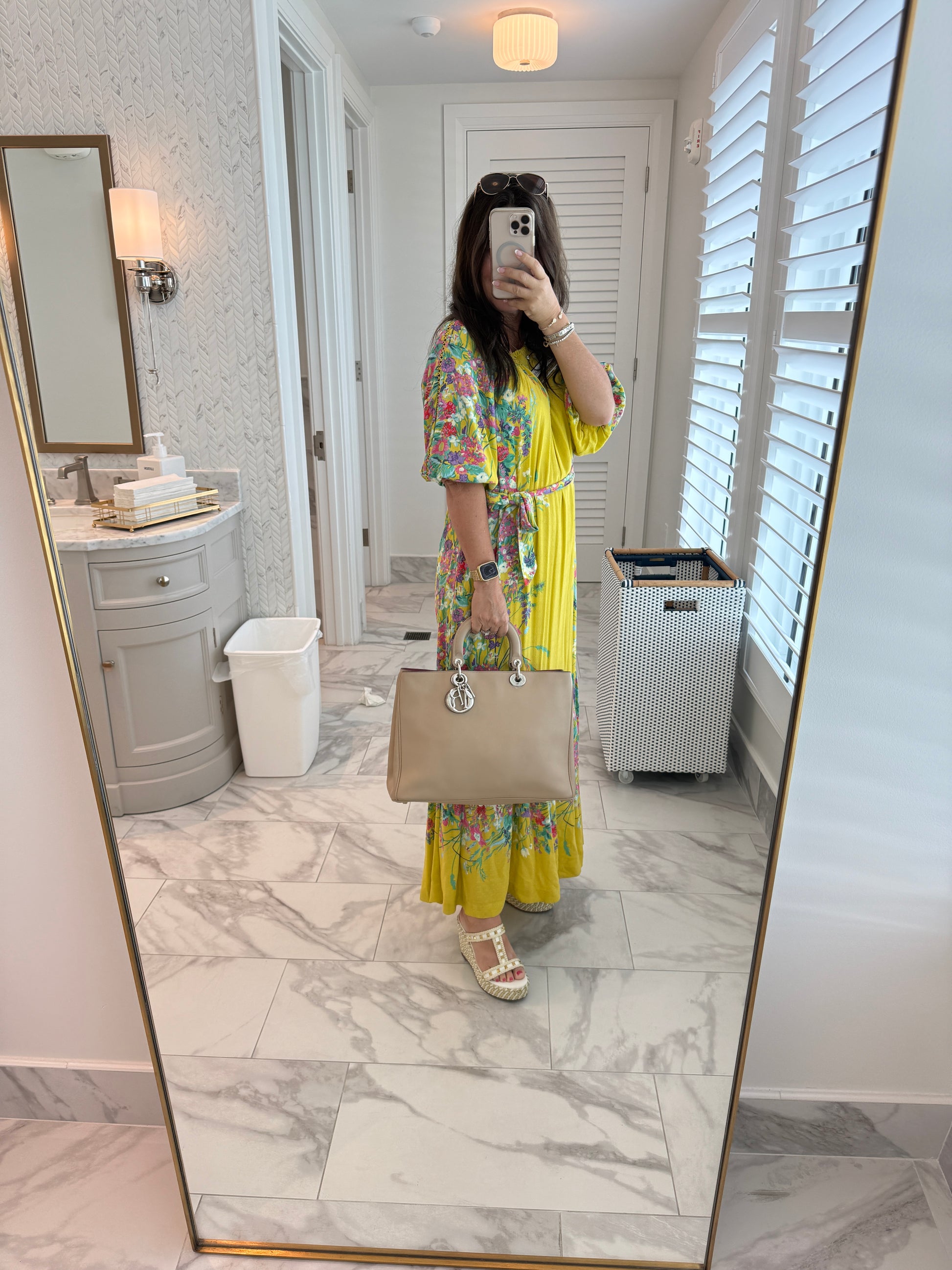 Dior diorissima tote in beige lambskin with silver hardware is hed by a woman using the top handles